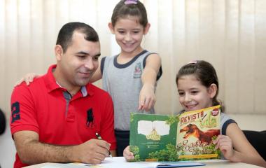 Márcio Pereira, de Joinville, voltou a estudar por causa das filhas Kamilly (em pé) e Kauany, gêmeas, de nove anos. Foto: Marcelo Kopcki