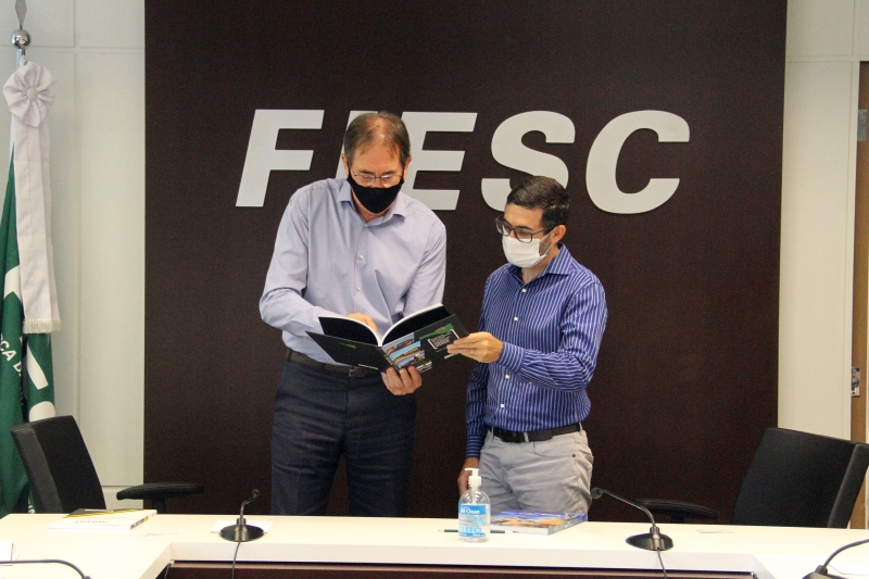 Aguiar (esq.) entregou ao secretário duas publicações que mostram as demandas de SC em Infraestrutura e o livro sobre os 70 anos da FIESC 