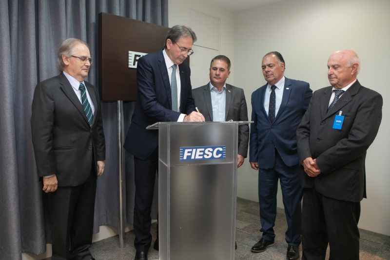 Mario Aguiar, presidente da FIESC, assina o convênio ao lado do secretário Altair Silva e empresários (foto: Filipe Scotti)