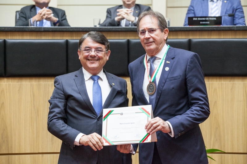Deputado Maurício Peixer (esq.) entrega homenagem ao presidente da FIESC, Mario Aguiar