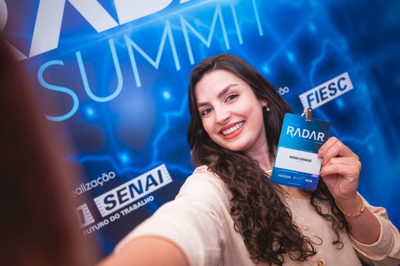 Participante exibe, feliz, credencial do evento realizado em Florianópolis