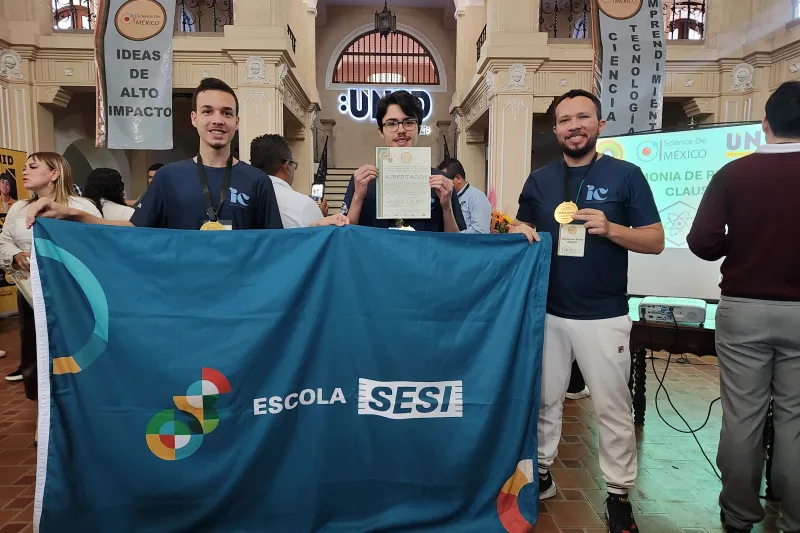 Alunos, ao lado do professor (barba), exibem bandeira da Escola SESI no México (Divulgação)